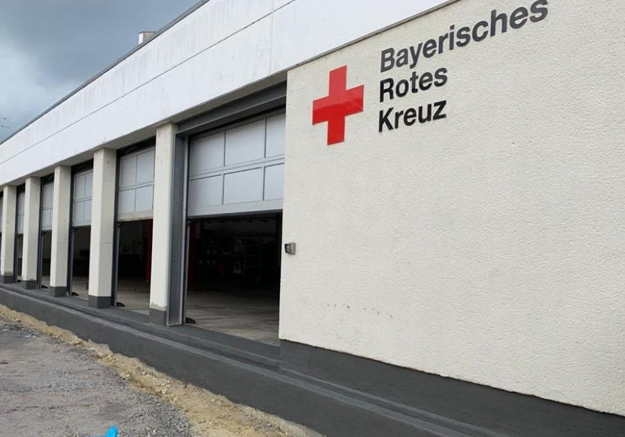 BRK-Gebäude in Plattling nach Betonsanierung, durchgehendes Sockelband und Schriftzug „Bayerisches Rotes Kreuz“.