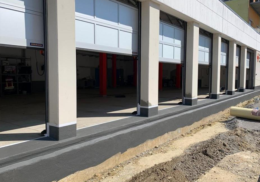 Sanierter Betonsockel an der Fahrzeughalle des BRK Plattling mit geöffneten Sektionaltoren.