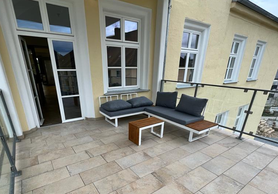 Balkonterrasse mit Natursteinbelag und Glasgeländer