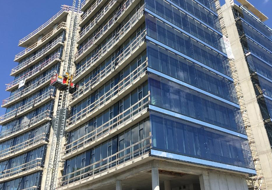 Hochhaus-Baustelle in Deggendorf mit montierter Glasfassade, Gerüsten und aktivem Bauaufzug.