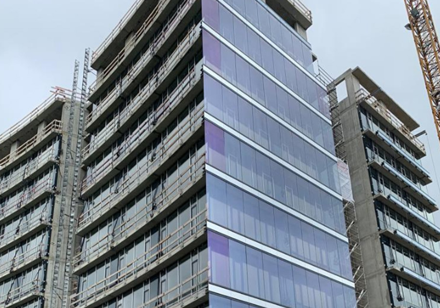 Neubau Büroturm Deggendorf mit geschwungener Glasfassade, Gerüsten und Bauaufzug während der Montage.