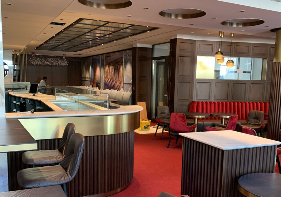 Lounge-Bereich mit gepolsterten Sitznischen, runden Tischen und dekorativen Leuchten im Kaffeehaus Deggendorf.