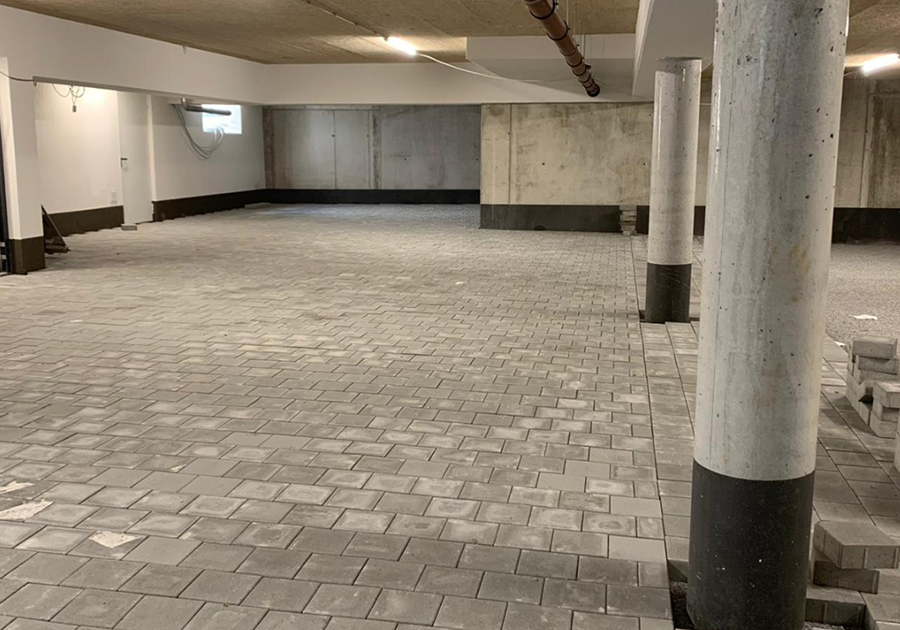 Das Bild zeigt eine Tiefgarage in Deggendorf mit neu verlegtem Pflasterbelag und einem regelmäßigen Raster aus runden Betonstützen, die die Decke tragen.